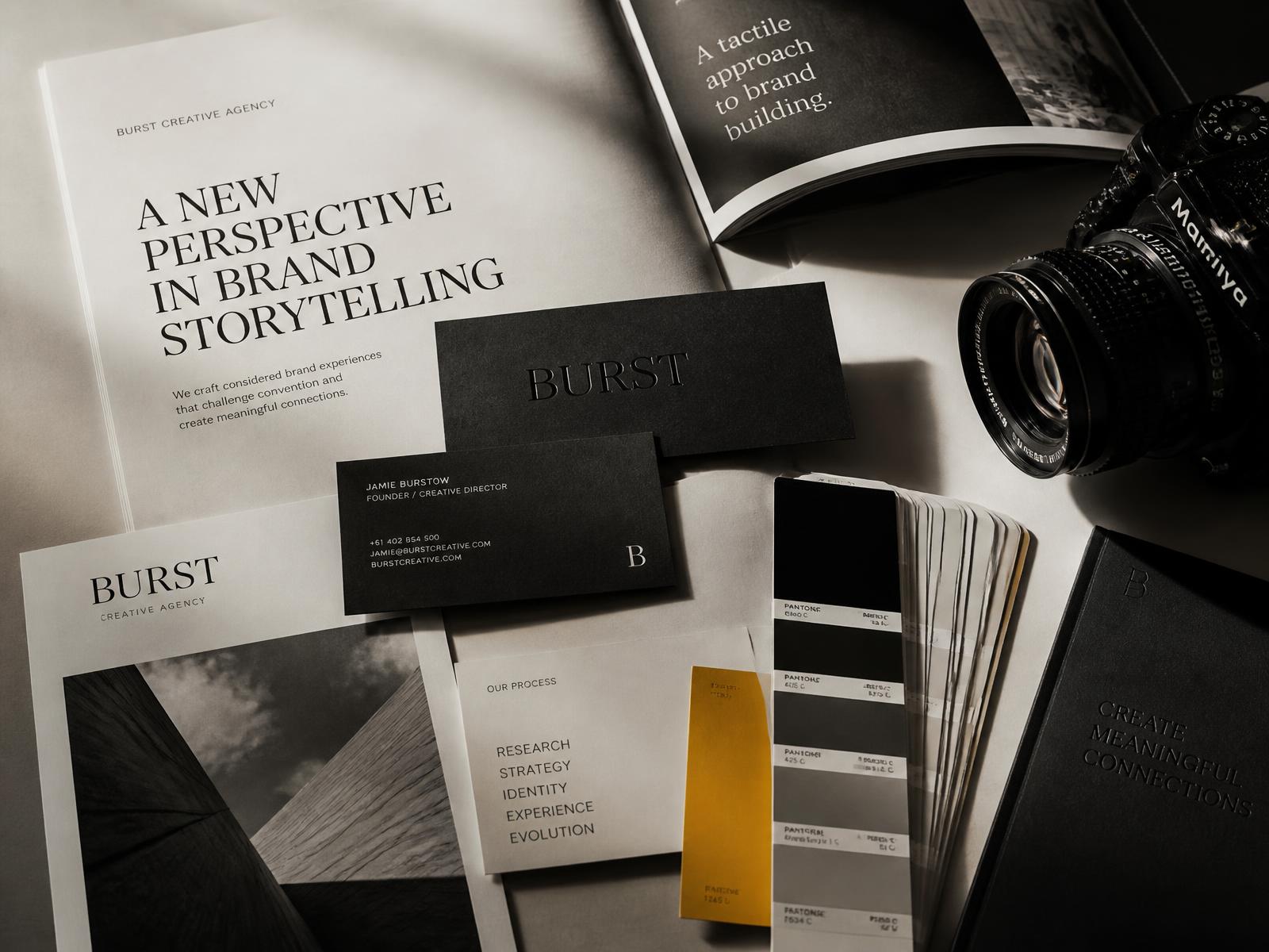 Brand identity print materials, editorial layouts and a camera arranged on a warm neutral surface